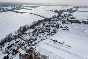 Winterlich schneebedeckte Dorf - Ansicht am Rande von landwirtschaftlichen Feldern und Nutzflächen in Vollmersweiler im Bundesland Rheinland-Pfalz, Deutschland