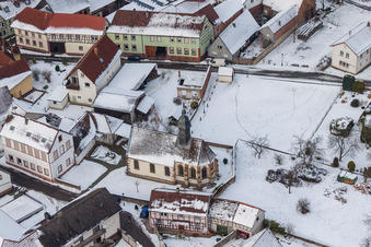 Winterlich schneebedeckte Kirchengebäude im Dorfkern in Dierbach im Bundesland Rheinland-Pfalz, Deutschland