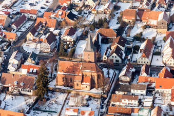 Winterlich schneebedeckte Kirchengebäude im Dorfkern in Rohrbach im Bundesland Rheinland-Pfalz, Deutschland