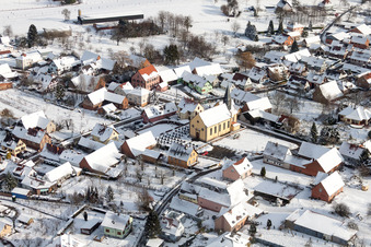 Winterlich schneebedeckte Kirchengebäude im Dorfkern in Oberlauterbach in Grand Est im Bundesland Bas-Rhin, Frankreich