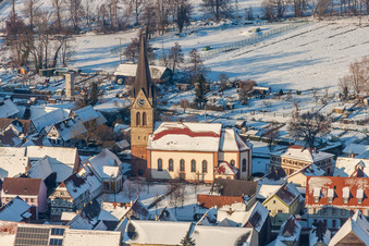 Luftaufnahme von Winterlich schneebedeckte Kirchengebäude der katholischen Kirche in der Dorfmitte in Steinweiler im Bundesland Rheinland-Pfalz, Deutschland