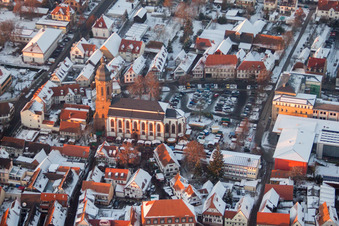 Winterlich schneebedeckte Kirchengebäude der Sankt Georgskirche mit Martplatz, Stadthalle und Grundschule im Altstadt- Zentrum in Kandel im Bundesland Rheinland-Pfalz, Deutschland