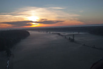 Luftaufnahme von Morgennebel beim Sonnenaufgang über Grasflächen- Strukturen einer Feld- und Wiesen- Landschaft Otterbachtal in Minfeld im Bundesland Rheinland-Pfalz, Deutschland