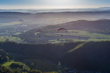 Wald und Berglandschaft mit 3 Paragleitern im Weserbergland in Holenberg im Bundesland Niedersachsen, Deutschland