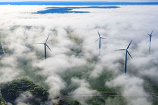 Schrägluftbild von Rotoren des Windpark Fürstenau ragen aus tiefen Wolken heraus in Höxter im Bundesland Nordrhein-Westfalen, Deutschland